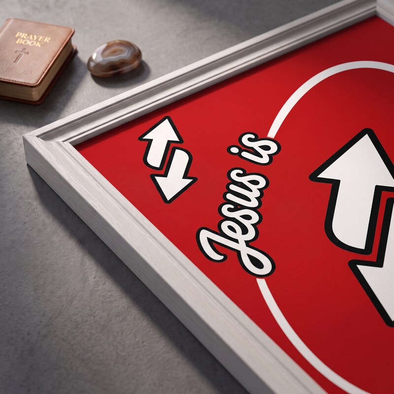 Angled close-up of the Jesus Is Everything red poster showing white arrows and black-outlined script.