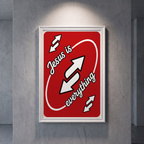 Jesus Is Everything red poster with white script and arrow graphics, shown in a white frame on a gray wall.