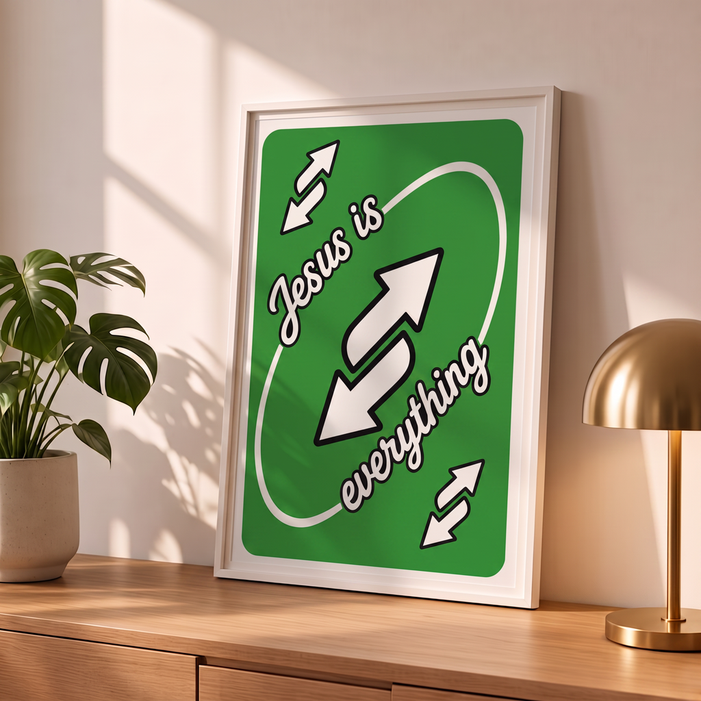 Jesus Is Everything green Christian poster in a styled tabletop mockup beside a plant and brass-colored lamp.
