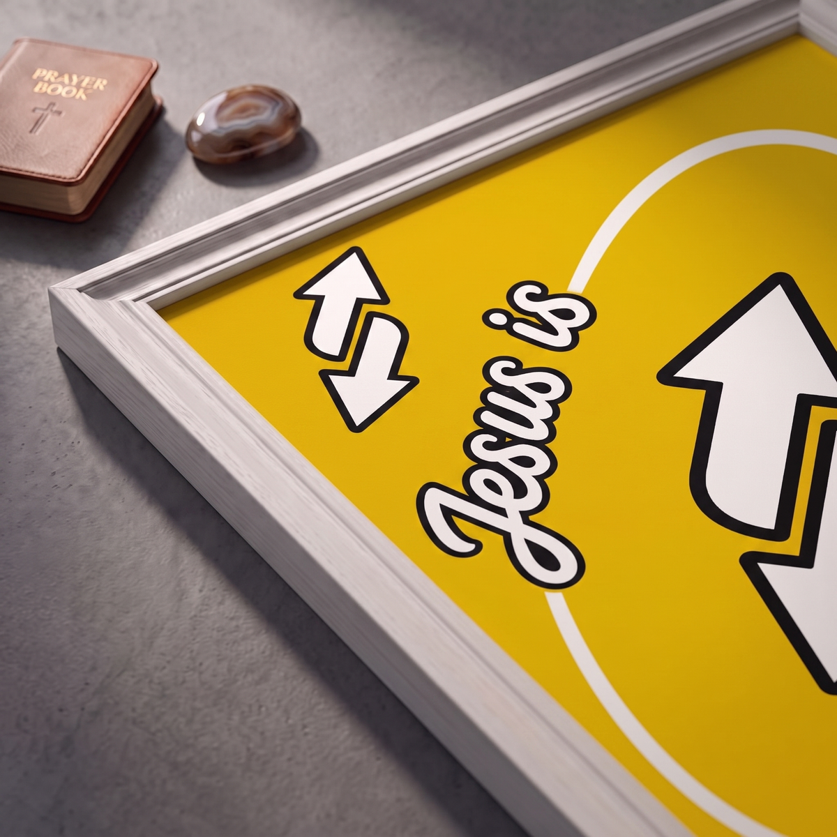 Angled close-up of the Jesus Is Everything yellow poster showing white arrows and black-outlined script.