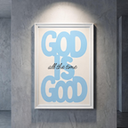 God Is Good blue typography poster with black “all the time” script on cream, shown in a white frame against a gray wall.
