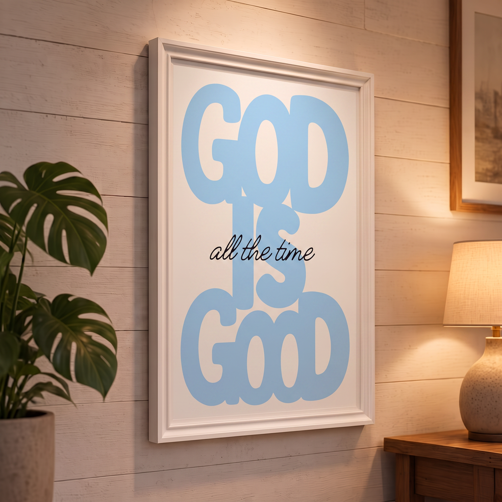 God Is Good blue Christian poster displayed in a white frame on a paneled wall beside a plant and lamp.