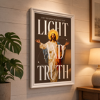 Light & Truth brown Jesus poster displayed on a paneled wall beside a plant and lamp.